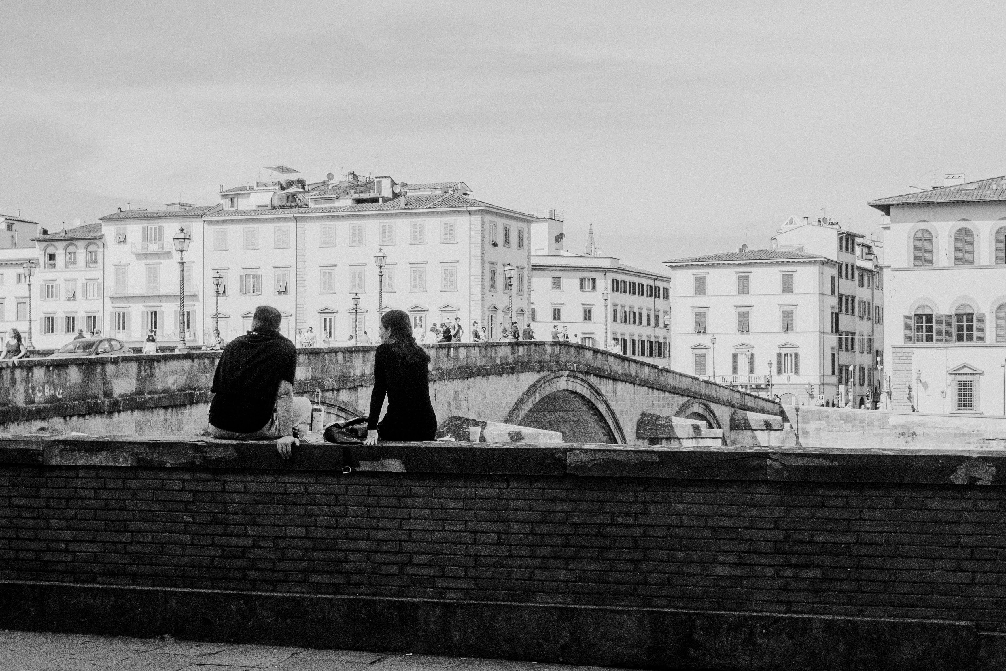two people sitting on a ledge talking